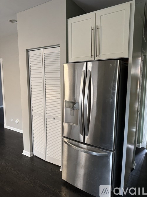 A stainless steel refrigerator with white doors and a white cabinet above it.