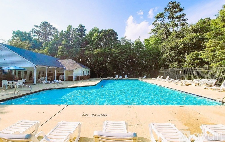 A pool surrounded by trees and chairs with a "No Diving" sign.