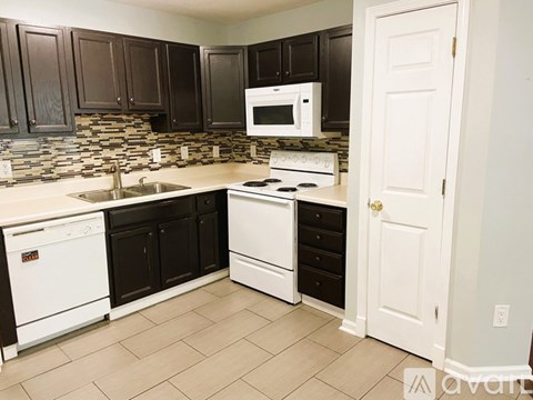 A kitchen with black cabinets and white appliances.
