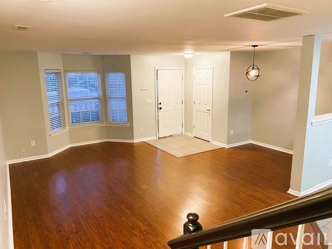 A room with wood flooring and a window with blinds.