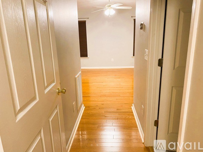 A long hallway with wood floors and white walls.