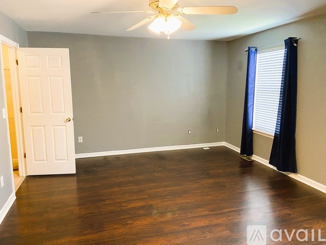 A room with a ceiling fan and wooden flooring.