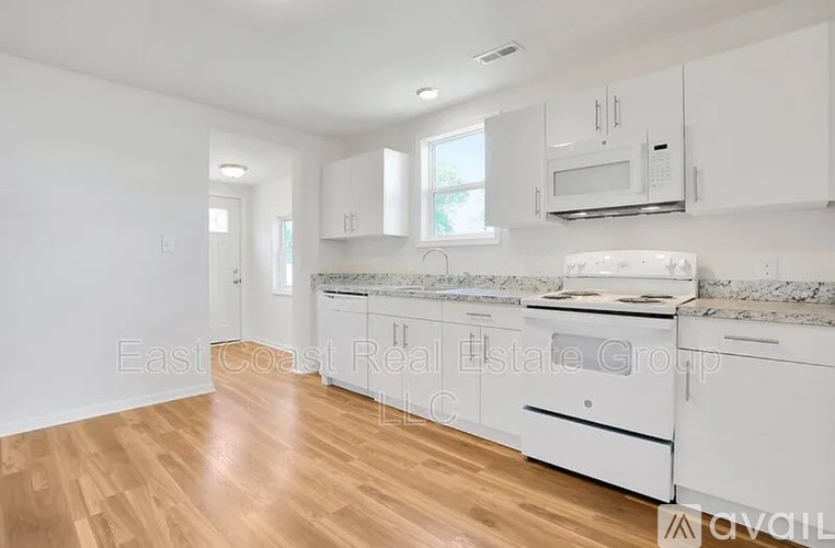 A kitchen with white cabinets and a white stove top oven.