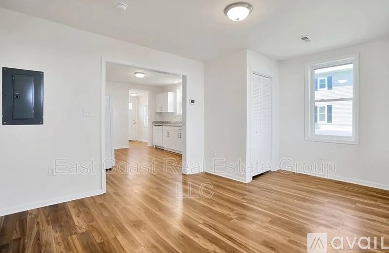 A spacious room with wooden floors and white walls.