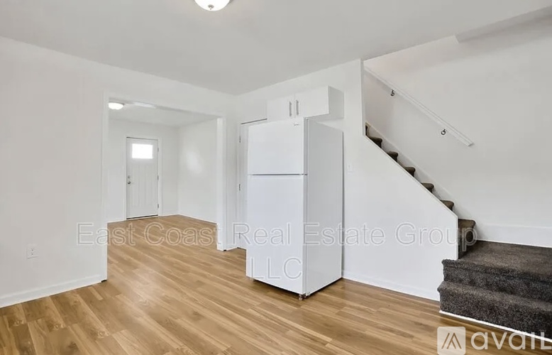 A spacious room with wooden floors and a staircase leading to another level.