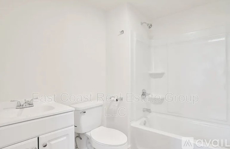 A white bathroom with a toilet, sink, and bathtub.