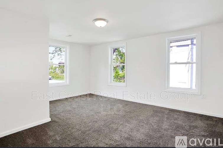 A room with a carpeted floor and two windows.
