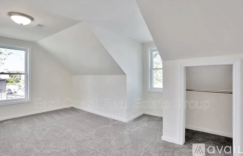 A spacious room with a carpeted floor and a window.