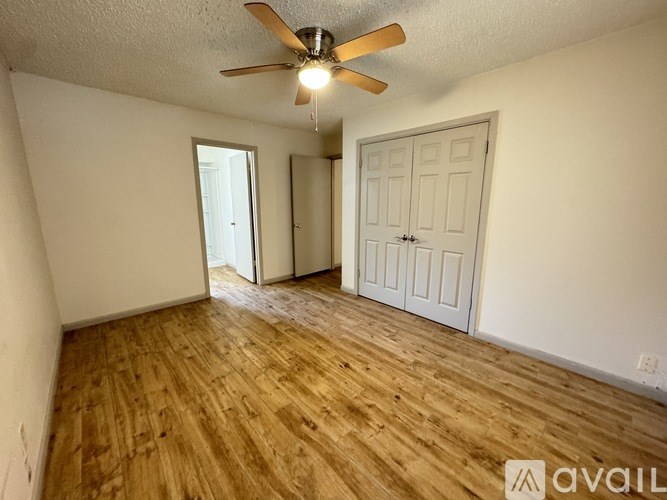 A room with a ceiling fan and wooden flooring.