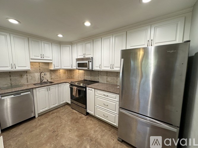 A kitchen with white cabinets and a stainless steel refrigerator.