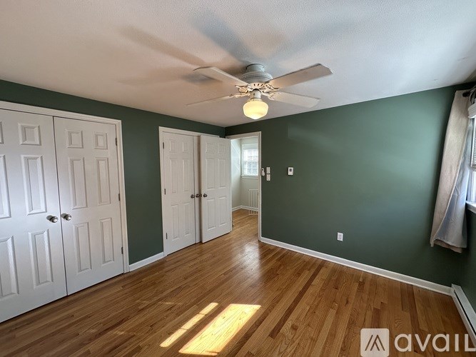 A room with a ceiling fan and wooden floors.