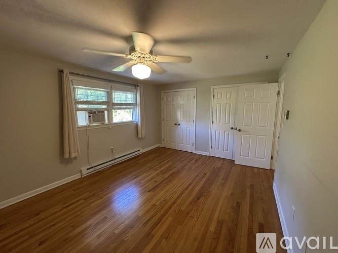 A room with a ceiling fan and wooden flooring.