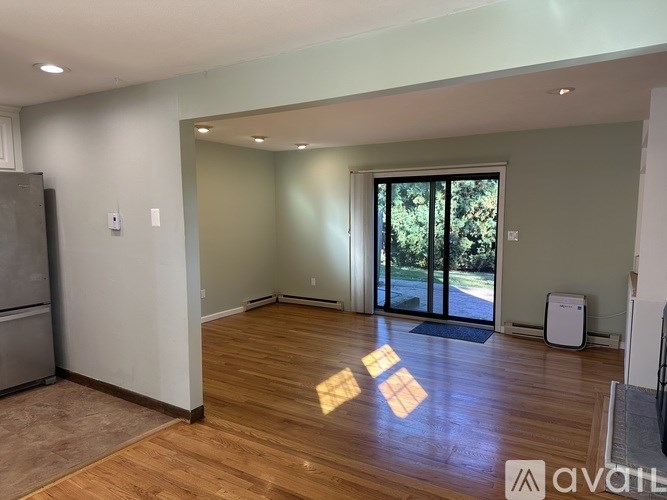 A room with wooden floors and a large window with a view of trees.
