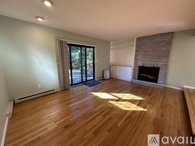 A room with wooden floors and a fireplace is available for rent.