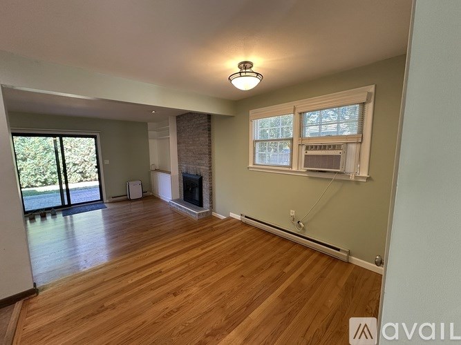 A room with wooden floors and a fireplace with a window above it.