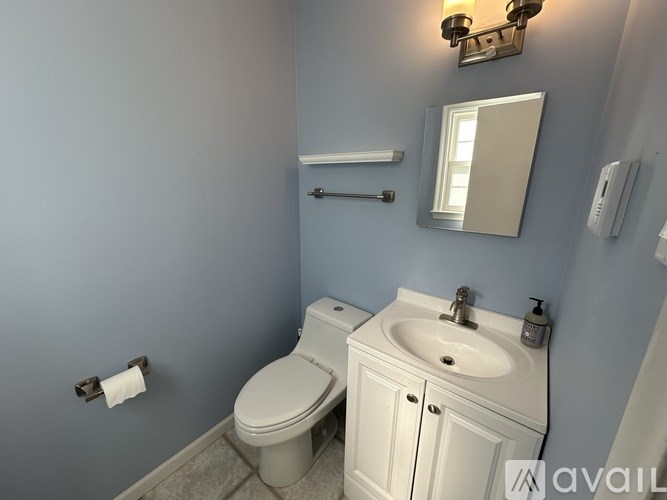 A bathroom with a toilet, sink, and mirror.