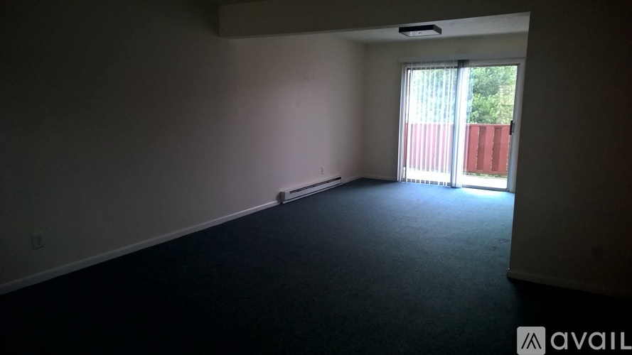 A bedroom with a bed, wooden floors, and a window with blinds.