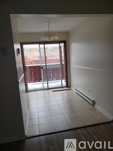 A room with a chandelier and sliding glass doors leading to a balcony.