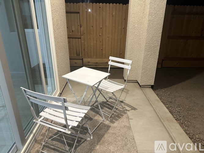 A white table and two chairs are on a patio.