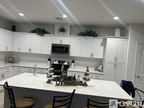 A kitchen with white cabinets and a white island with a tree on it.