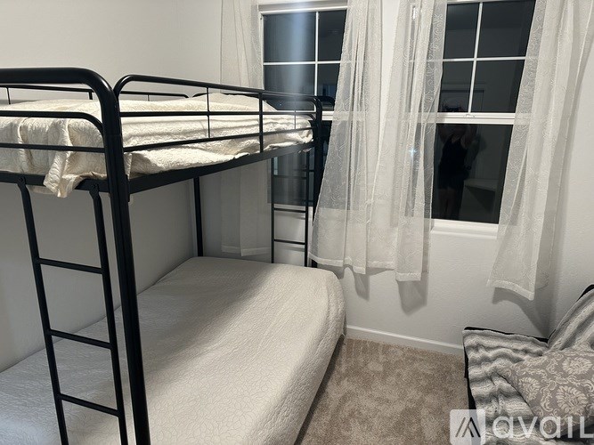 A white bed with a white blanket and a white pillow is in a room with a window.
