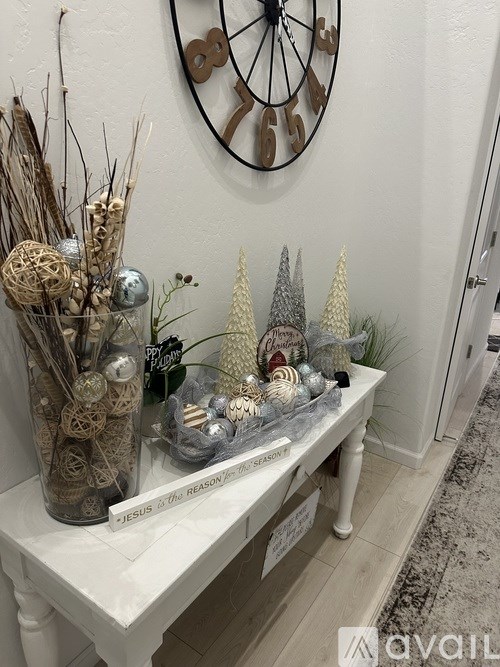 A white table with a glass container, a jar, and a sign that says "JESUS IS THE REASON FOR THE CHRISTMAS".