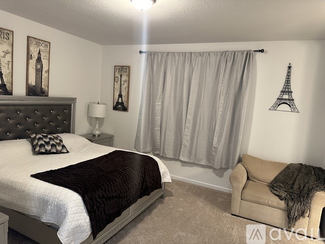 A bedroom with a bed, a couch, and pictures of the Eiffel Tower on the wall.
