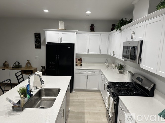 A kitchen with white cabinets and a black fridge.