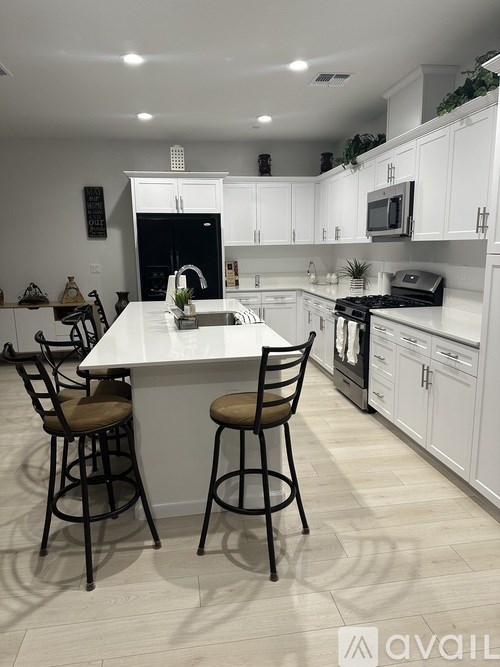 A kitchen with white cabinets and a black fridge.