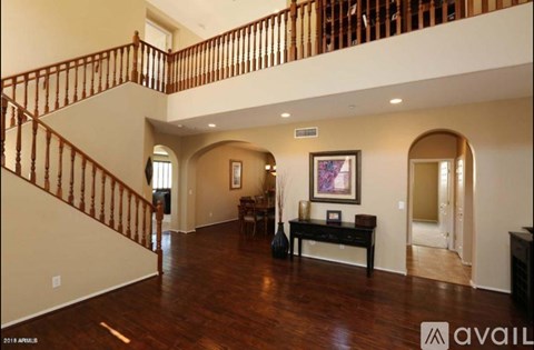 A spacious living room with a staircase and a painting on the wall.