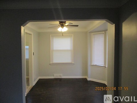 A room with a ceiling fan and two windows.