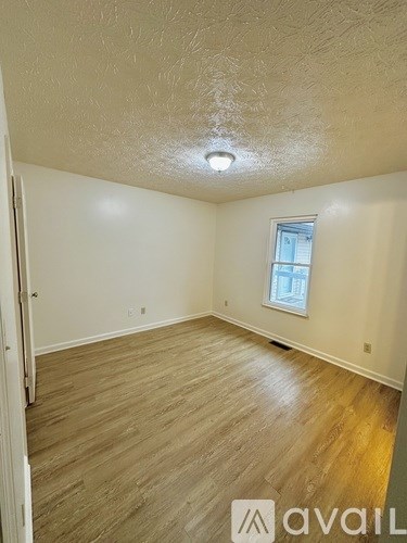 A room with wooden flooring and a window.