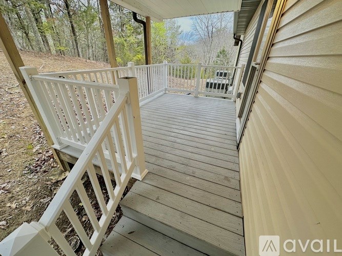 A wooden deck with a white railing and a view of a wooded area.