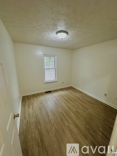 A room with wooden flooring and a window.