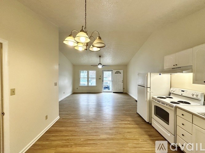 A kitchen with white appliances and wooden floors.