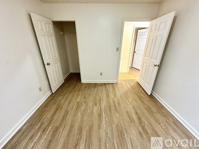 A room with wooden flooring and two white doors.