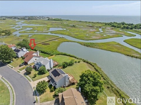 A bird's eye view of a residential area with a body of water and a red arrow pointing to a specific location.
