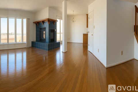 A living room with a blue tiled fireplace and wooden floors.