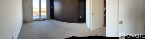 A carpeted room with a door and a window.