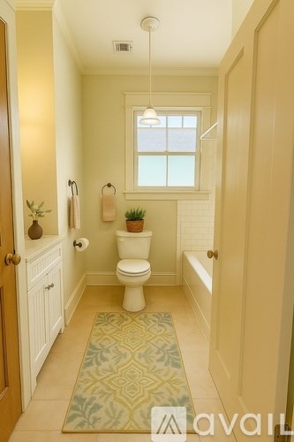 A bathroom with a toilet, a window, and a rug.