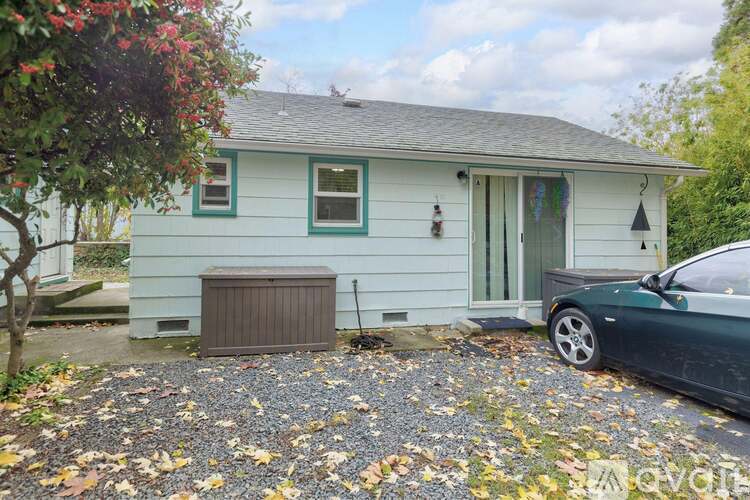 A small house with a green car parked in front.