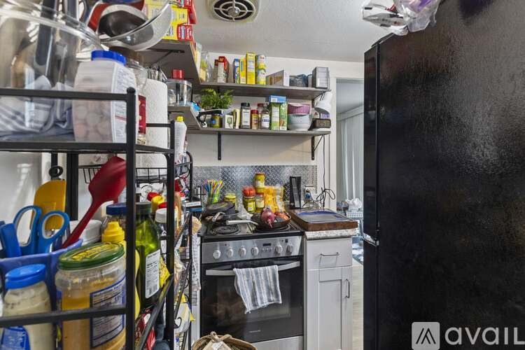 A kitchen with a black refrigerator and a stove with a pot on it.