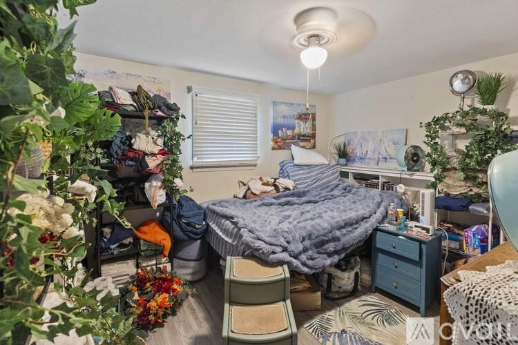 A bedroom with a bed, a chair, and a potted plant.