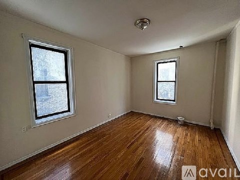 A room with wooden floors and two windows.