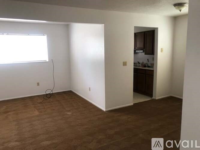A room with a window and a door leading to a kitchen.