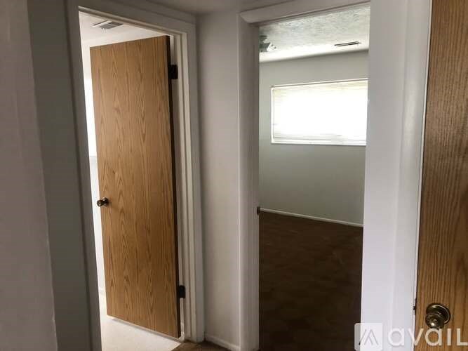 A wooden door is open to a room with a window.