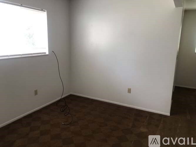 A room with a window and a brown floor.