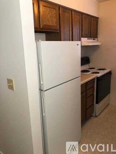 A white refrigerator in a kitchen with wooden cabinets.
