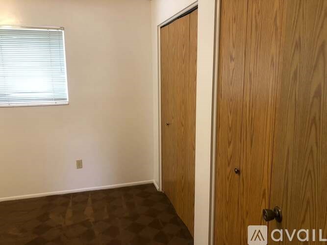 A room with a wooden door and a window with blinds.