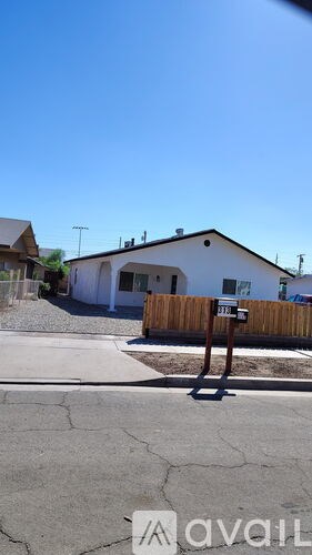 A house with a white exterior and a brown fence is shown in the image.